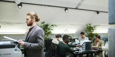 En person går gjennom et kontorlandskap. Foto