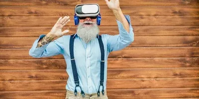 En eldre mann står med VR-headset og hendene i været. Foto